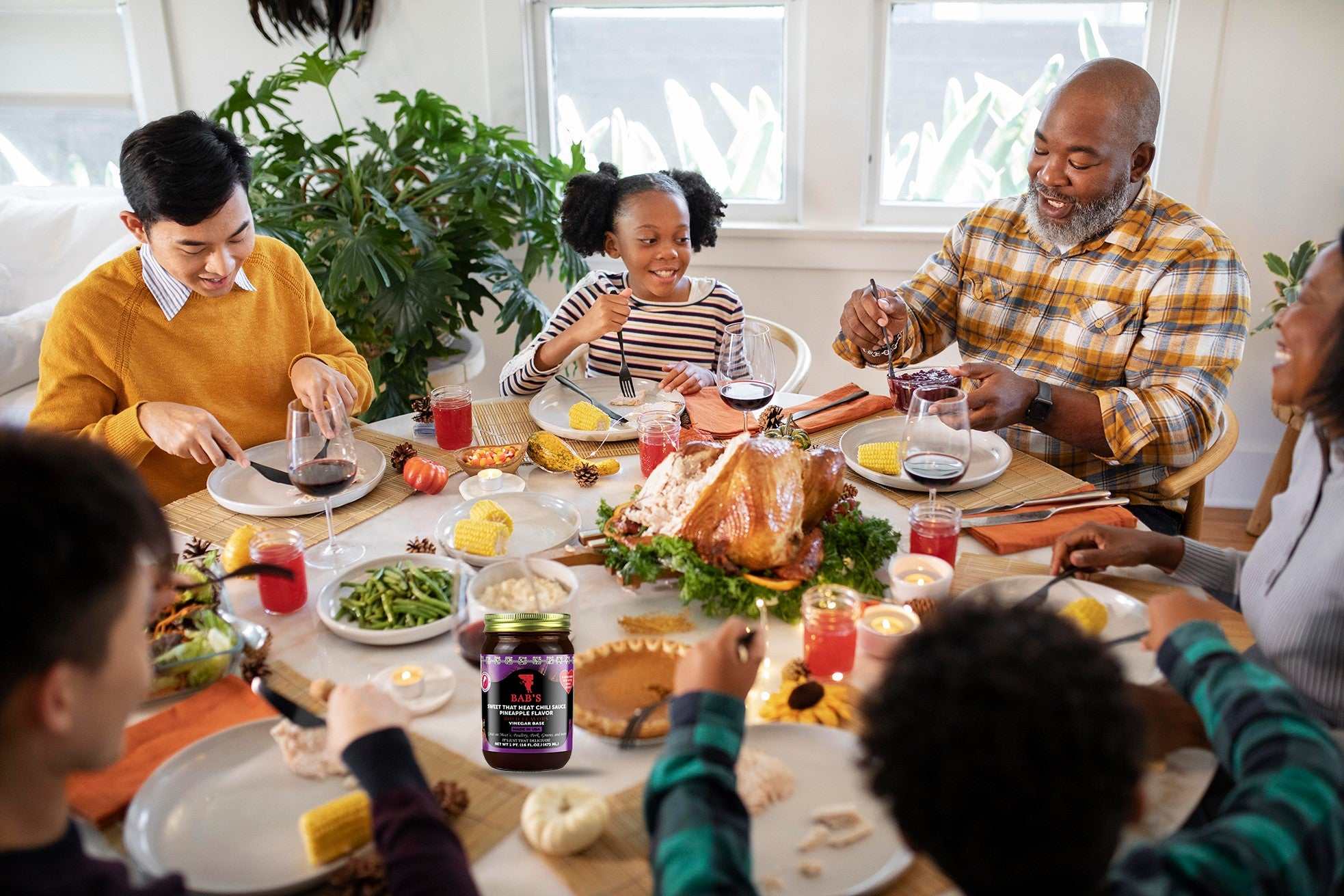 Family enjoying meal with Sweet That Heat Chili Sauce pineapple flavor on the table.